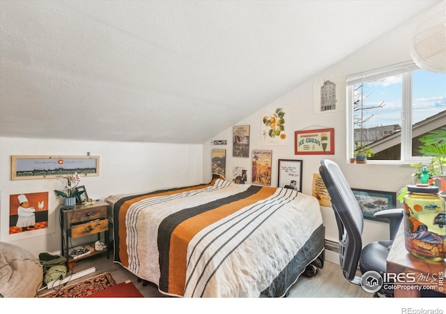 bedroom with vaulted ceiling and wood finished floors