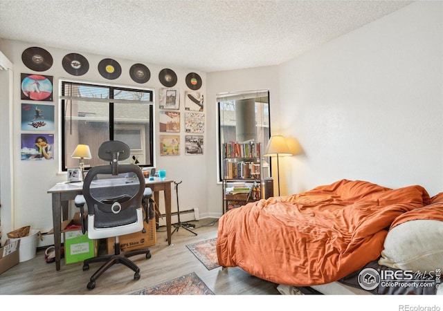 bedroom with a baseboard radiator, a textured ceiling, and wood finished floors