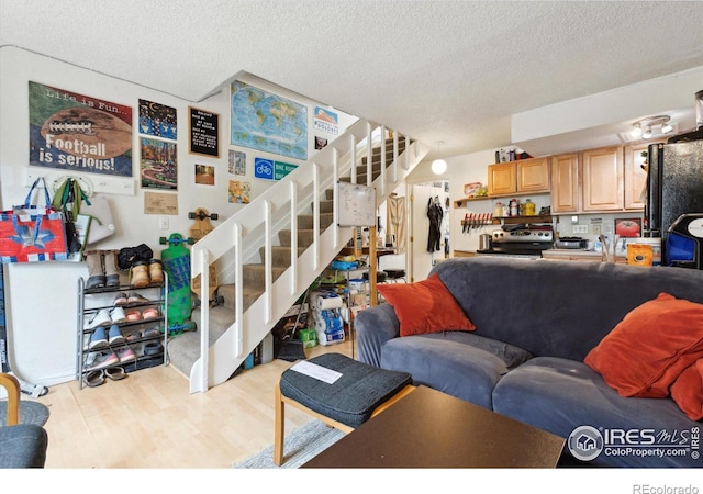living area featuring a textured ceiling, stairs, and wood finished floors