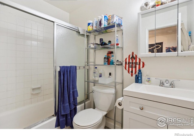 full bath with toilet, shower / bath combination with glass door, and vanity
