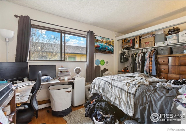 bedroom with a closet, a textured ceiling, and wood finished floors