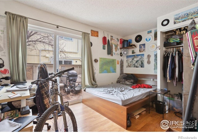 bedroom featuring a closet, wood finished floors, and a textured ceiling
