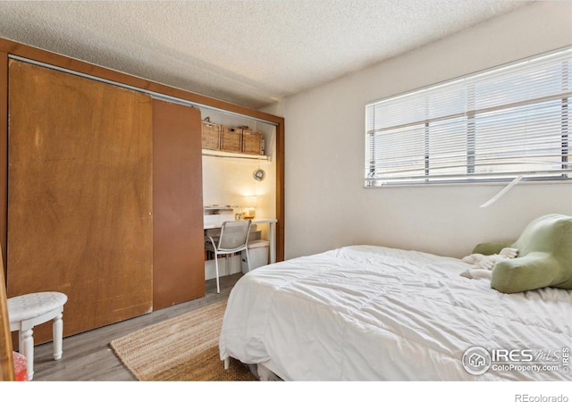 bedroom featuring light wood-type flooring, a closet, and a textured ceiling