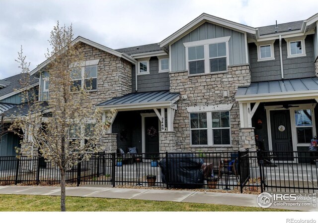 2449 Trio Falls Dr, Loveland, CO 80538 - townhome / multi-family property featuring board and batten siding, ceiling fan, a standing seam roof, a fenced front yard, and stone siding