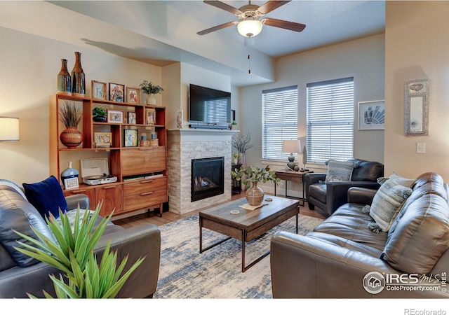 2449 Trio Falls Dr, Loveland, CO 80538 - living area featuring a fireplace, a ceiling fan, and light wood-style flooring