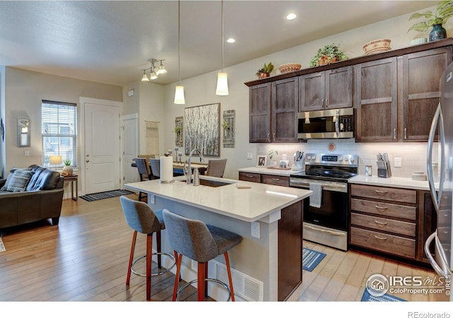 2449 Trio Falls Dr, Loveland, CO 80538 - kitchen featuring appliances with stainless steel finishes, light wood-type flooring, a sink, light countertops, and open floor plan