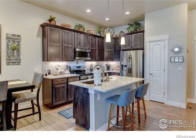 2449 Trio Falls Dr, Loveland, CO 80538 - kitchen with a sink, dark brown cabinetry, stainless steel appliances, and light wood finished floors