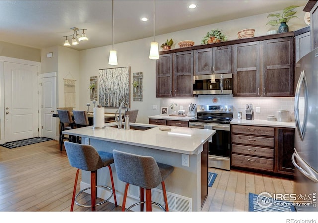 2449 Trio Falls Dr, Loveland, CO 80538 - kitchen featuring light wood-type flooring, a sink, appliances with stainless steel finishes, and a kitchen bar