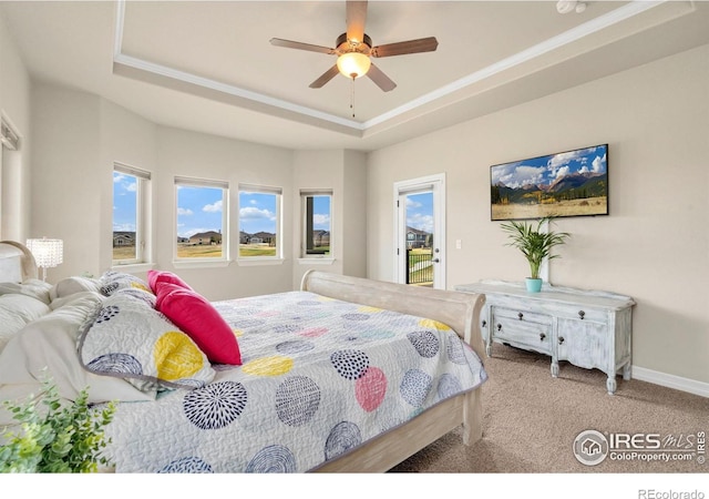 carpeted bedroom with baseboards, access to exterior, ornamental molding, and a raised ceiling