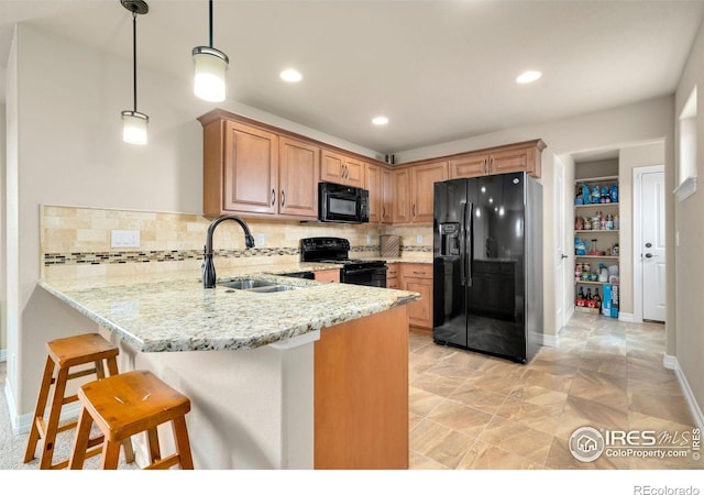 kitchen with a peninsula, light stone countertops, a sink, backsplash, and black appliances
