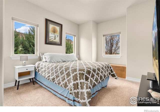 carpeted bedroom featuring baseboards and multiple windows