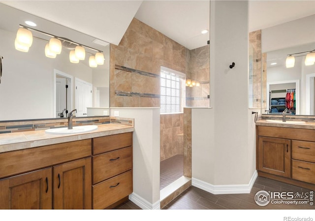 bathroom featuring a walk in shower, baseboards, wood finished floors, and vanity