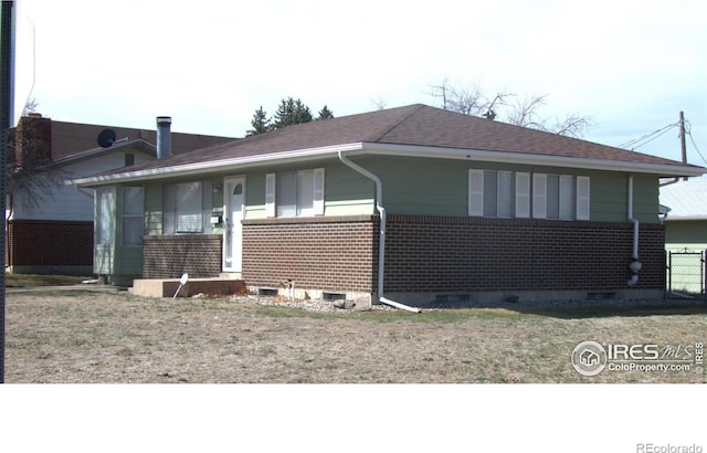 view of side of home with brick siding, a yard, and crawl space