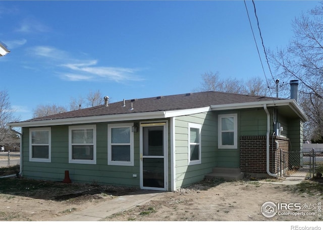 rear view of house featuring fence and a shingled roof