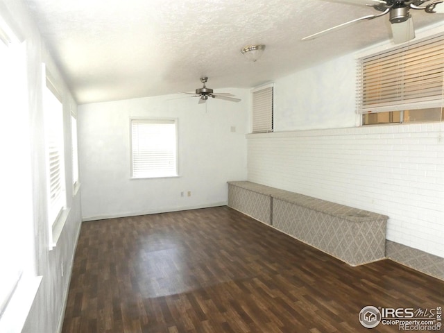 spare room with a textured ceiling, vaulted ceiling, wood finished floors, and ceiling fan