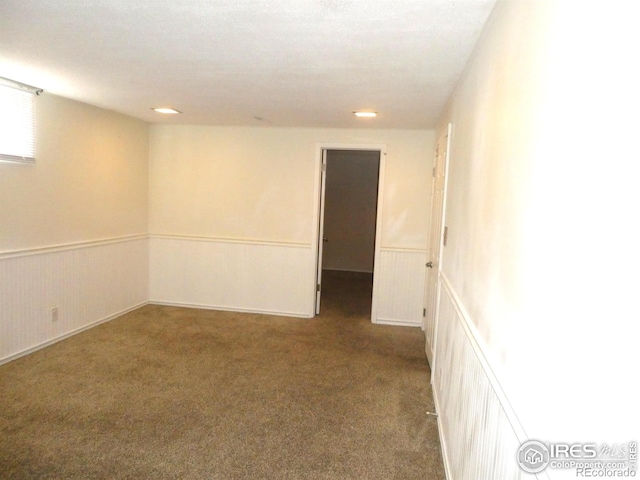 carpeted spare room featuring a wainscoted wall