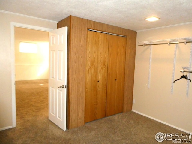 unfurnished bedroom featuring a closet, baseboards, ornamental molding, and carpet