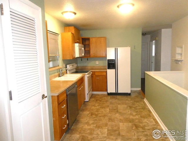 kitchen with white appliances, light countertops, open shelves, brown cabinets, and a sink