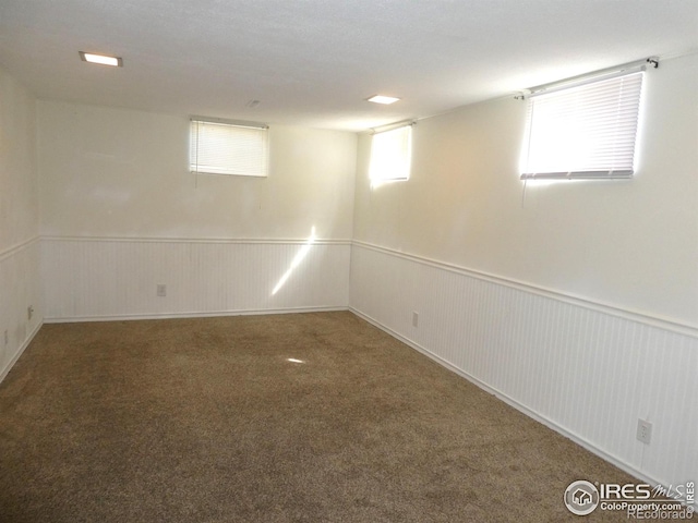 below grade area featuring carpet flooring and a wainscoted wall