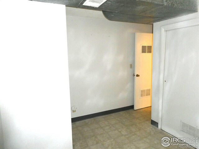 empty room with visible vents, baseboards, and light floors
