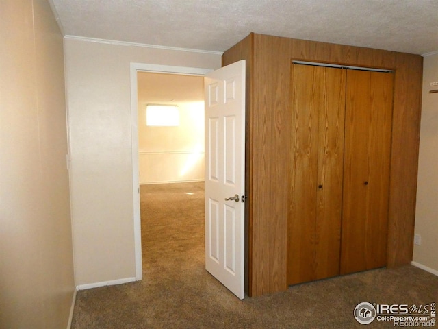 unfurnished bedroom with crown molding, a closet, baseboards, and carpet