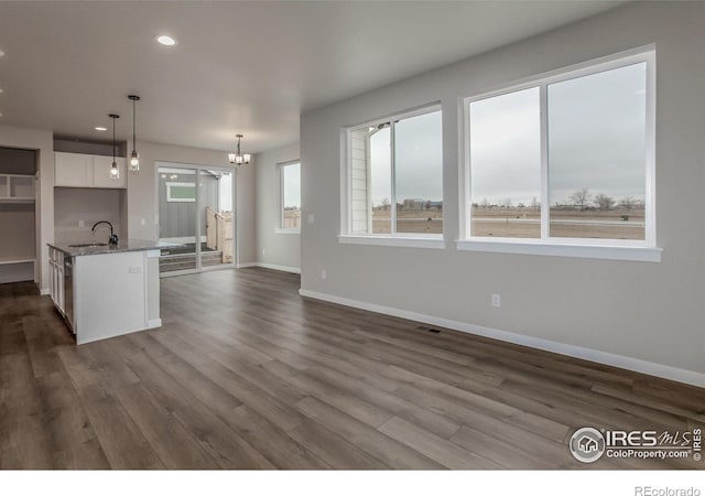 1219 105th Avenue Ct, Greeley, CO 80634 - kitchen featuring pendant lighting, stone countertops, baseboards, white cabinets, and dark wood-style flooring