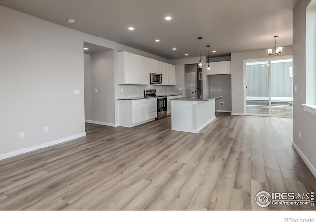 1219 105th Avenue Ct, Greeley, CO 80634 - kitchen with open floor plan, white cabinets, stainless steel appliances, and a notable chandelier