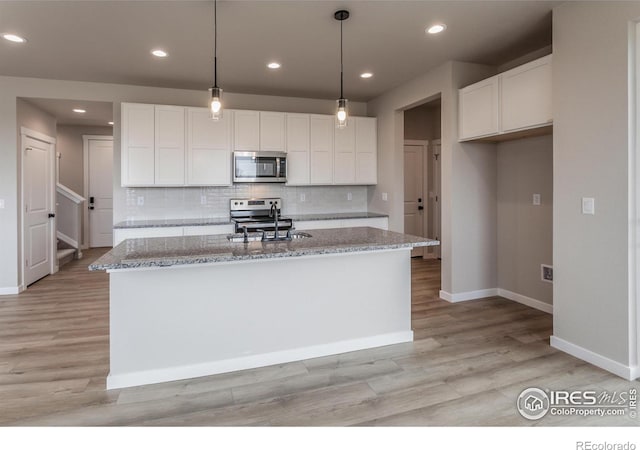 1219 105th Avenue Ct, Greeley, CO 80634 - kitchen with white cabinetry, light wood-style flooring, stainless steel appliances, and light stone countertops
