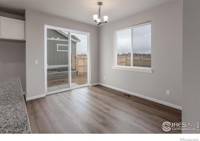 1219 105th Avenue Ct, Greeley, CO 80634 - unfurnished dining area with baseboards, visible vents, an inviting chandelier, and wood finished floors