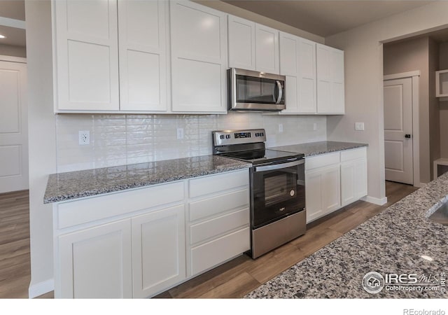 1219 105th Avenue Ct, Greeley, CO 80634 - kitchen featuring decorative backsplash, white cabinets, wood finished floors, appliances with stainless steel finishes, and stone countertops