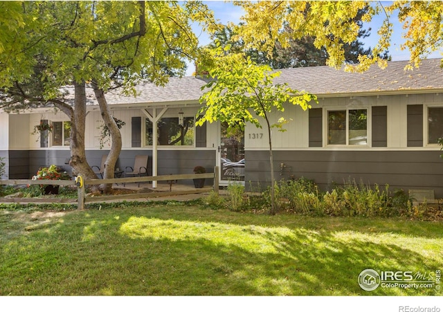 ranch-style home featuring fence, roof with shingles, and a front yard