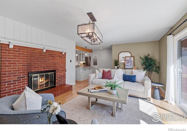 living room featuring an inviting chandelier, a fireplace, and wood finished floors