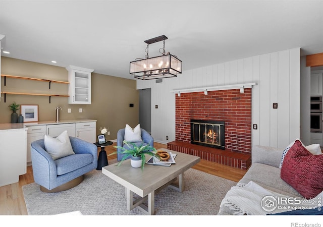 living room with light wood-style floors, recessed lighting, and a brick fireplace