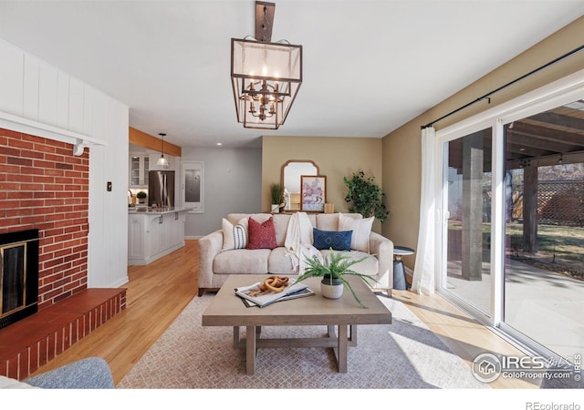 living area with light wood finished floors, a fireplace, and a chandelier