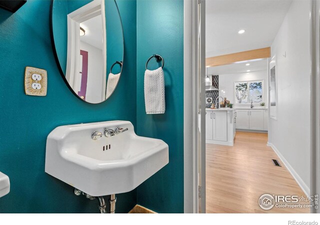 bathroom featuring wood finished floors, a sink, baseboards, and visible vents