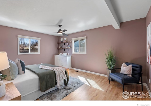 bedroom with visible vents, baseboards, wood finished floors, a ceiling fan, and beam ceiling