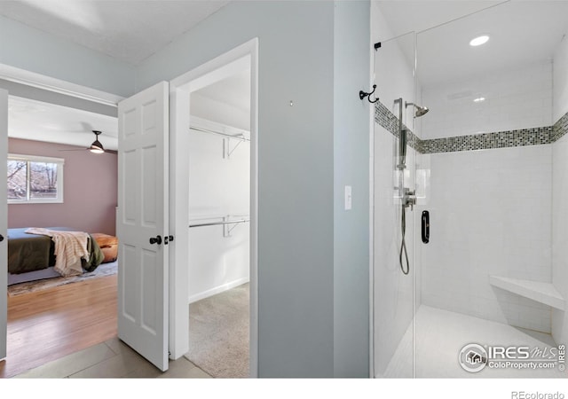 ensuite bathroom featuring a shower stall, ensuite bath, ceiling fan, and a spacious closet
