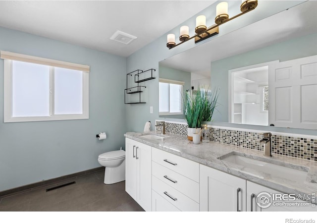 bathroom with toilet, a sink, tasteful backsplash, and visible vents