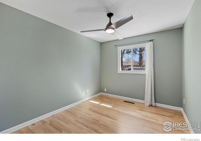 empty room with a ceiling fan, wood finished floors, baseboards, and visible vents