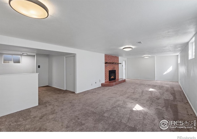 unfurnished living room featuring carpet flooring, visible vents, and a brick fireplace