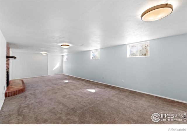 basement with baseboards, carpet, and a brick fireplace