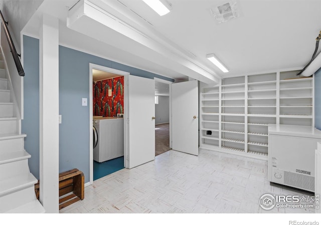 finished basement with stairs, visible vents, and washer / dryer