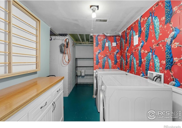 clothes washing area with washing machine and clothes dryer, cabinet space, and visible vents