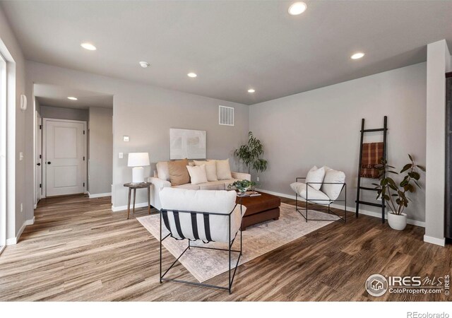 living area featuring visible vents, baseboards, recessed lighting, and wood finished floors