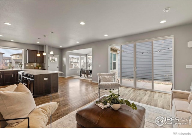 living room with baseboards, recessed lighting, and light wood-style floors