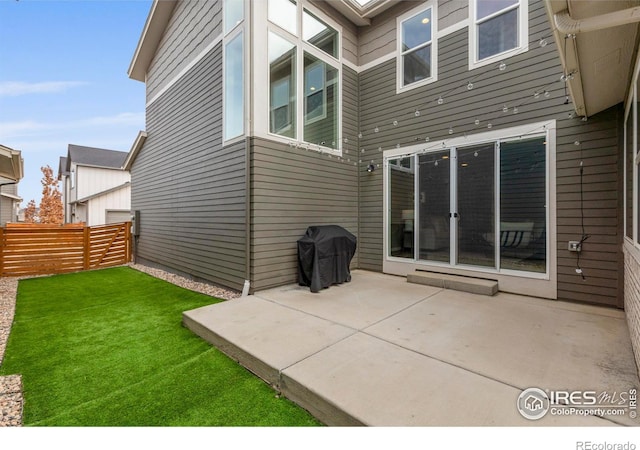 rear view of property featuring fence, a yard, and a patio area