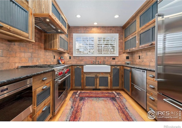 5125 Stetson Creek Ct Unit D, Fort Collins, CO 80528 - kitchen with premium appliances, a sink, custom range hood, decorative backsplash, and light wood-style floors