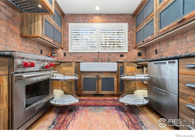 5125 Stetson Creek Ct Unit D, Fort Collins, CO 80528 - kitchen featuring stainless steel appliances, a sink, wood finished floors, exhaust hood, and glass insert cabinets