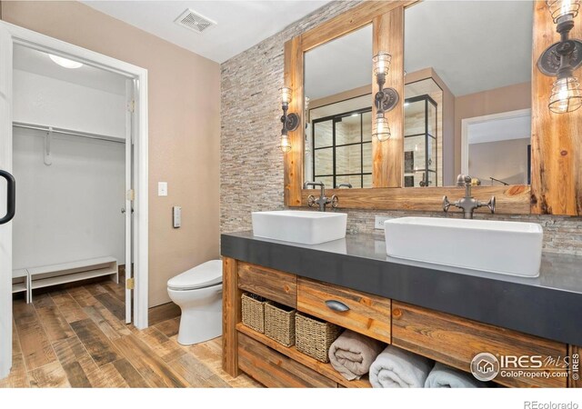 5125 Stetson Creek Ct Unit D, Fort Collins, CO 80528 - bathroom with a baseboard heating unit, wood finished floors, double vanity, toilet, and a walk in closet