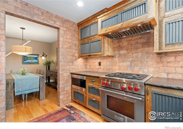 5125 Stetson Creek Ct Unit D, Fort Collins, CO 80528 - kitchen with premium range, light wood finished floors, dark countertops, custom exhaust hood, and pendant lighting